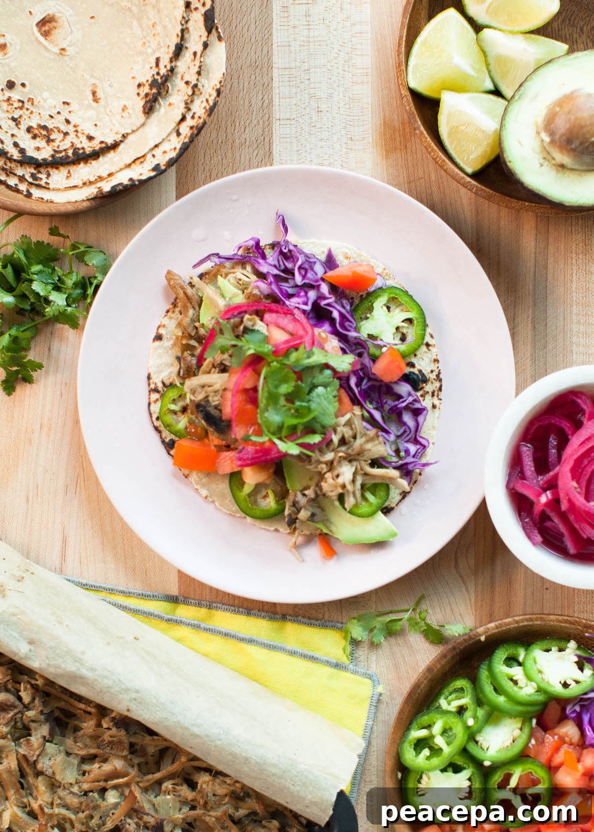 overhead of mushroom carnitas tacos on a wooden background surrounded by colorful toppings