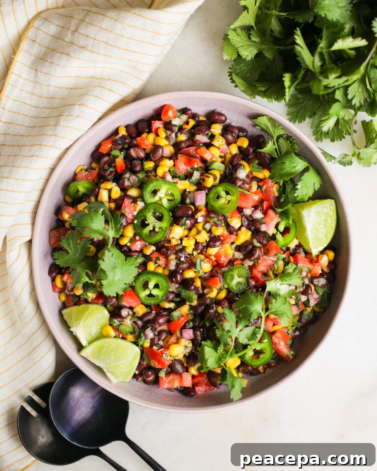 An overhead shot of a bowl of black bean and corn salad with lime, cilantro, and jalapenos.
