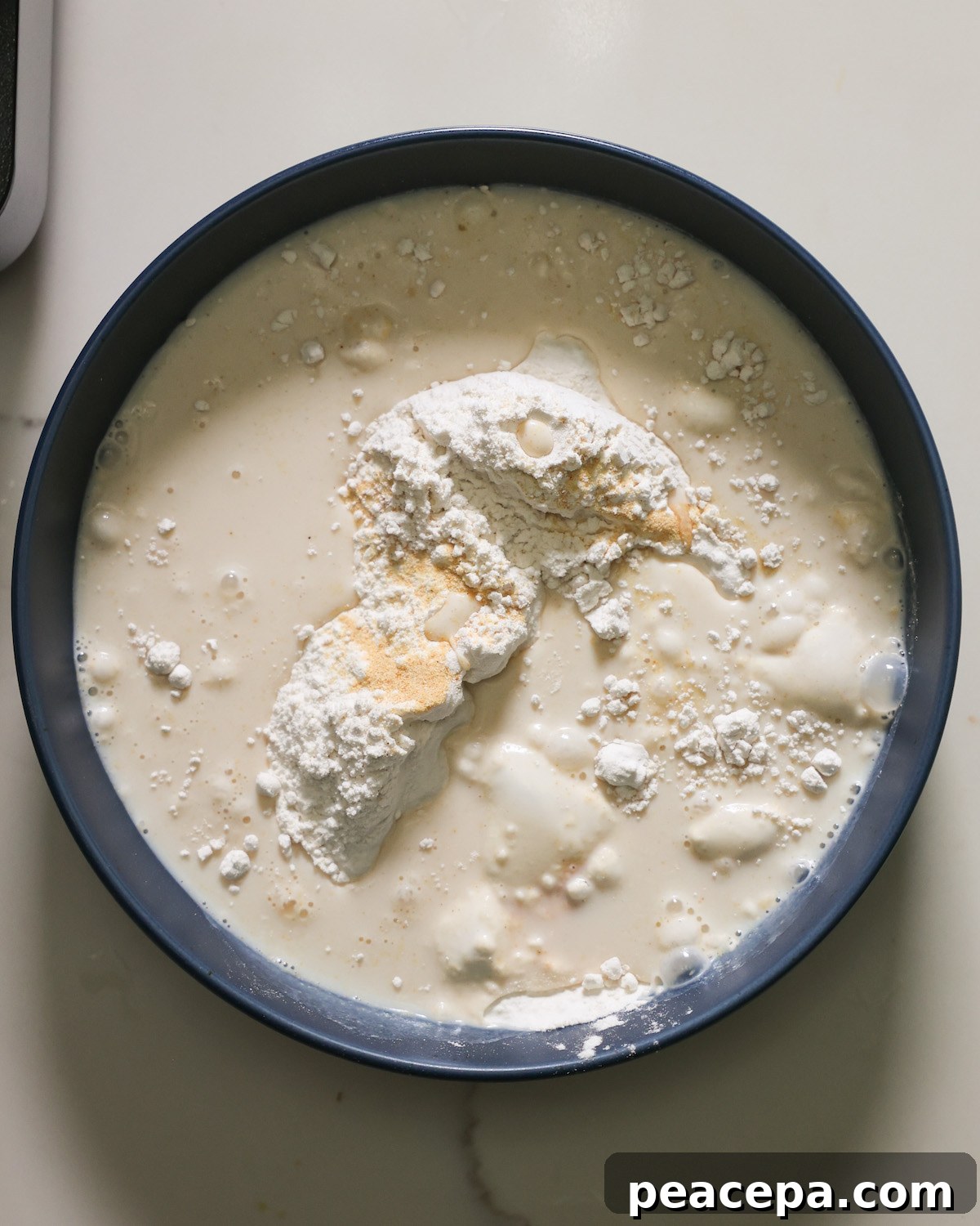 Adding the flour to the bowl of liquids to make the cauliflower batter.