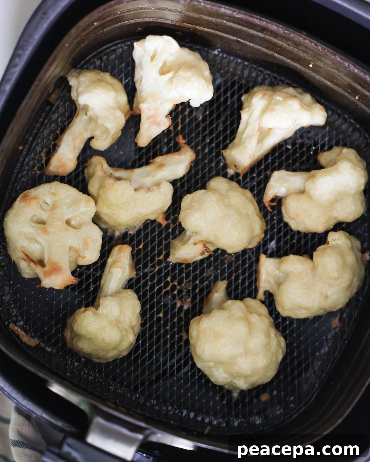 An overhead shot of air fried cauliflower in a basket of an air fryer.