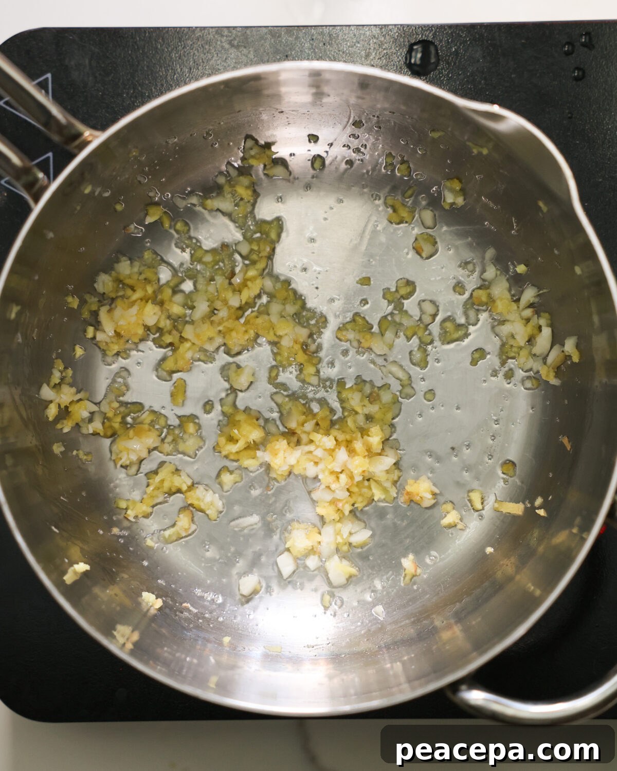 An overhead shot of minced garlic sauteeing in a pan.