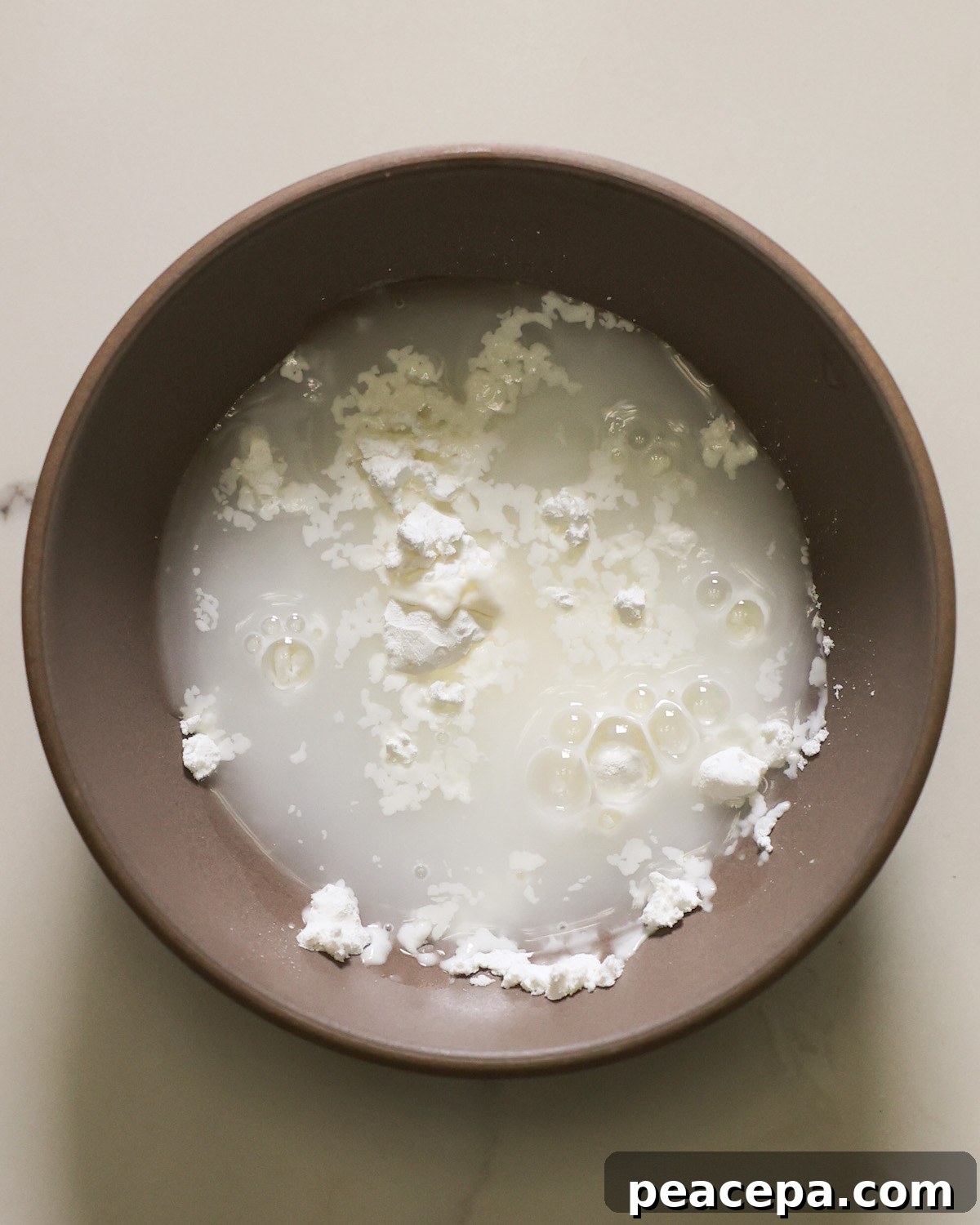 A small tan bowl of cornstarch and milk.