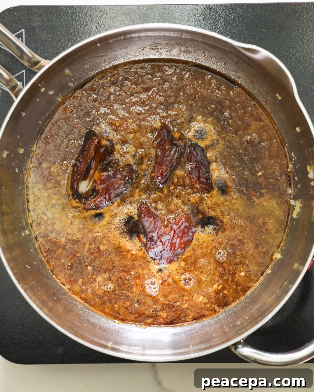 An ovheread shot of a pan of the orange sauce and dates.