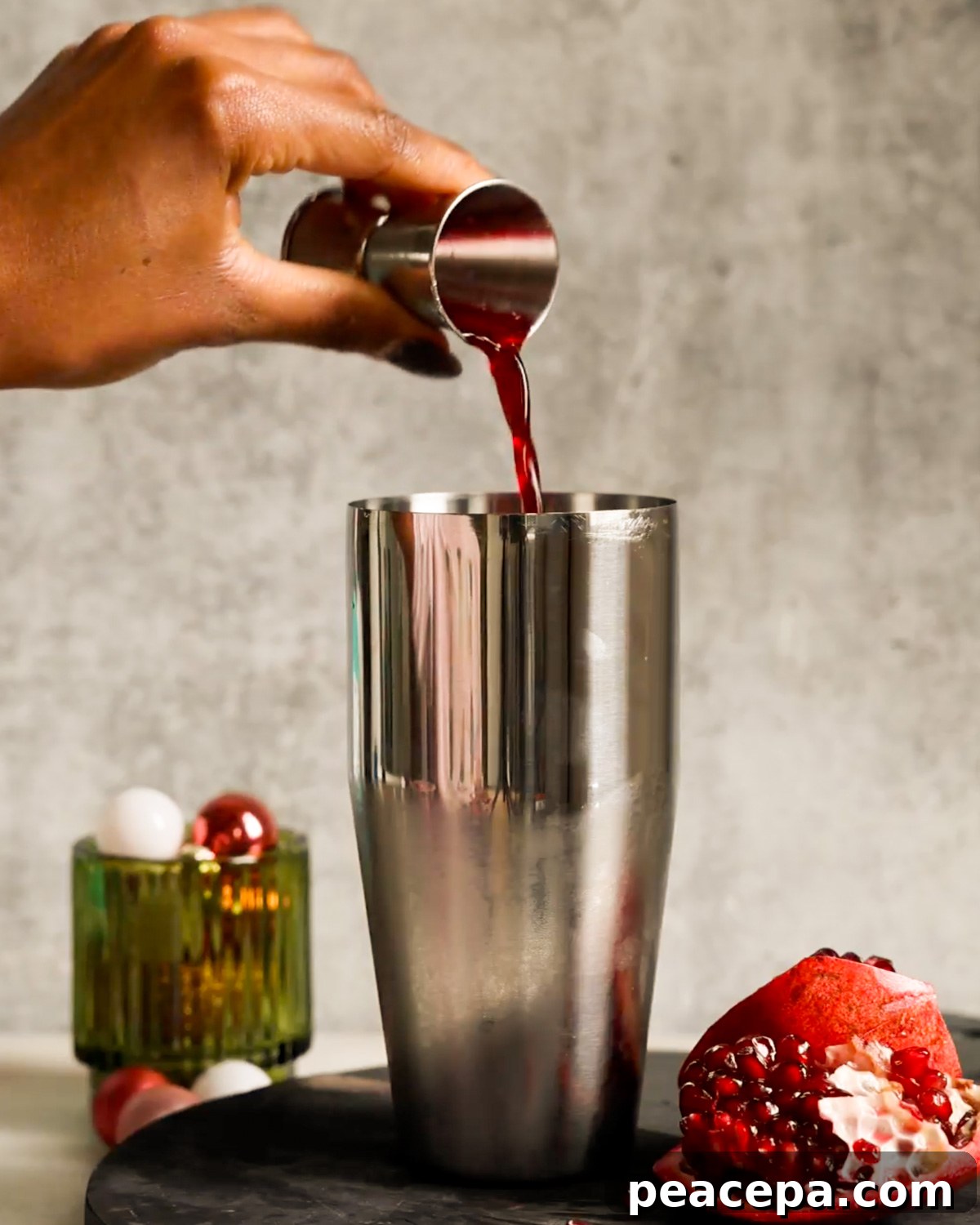 adding pomegranate juice to cocktail shaker