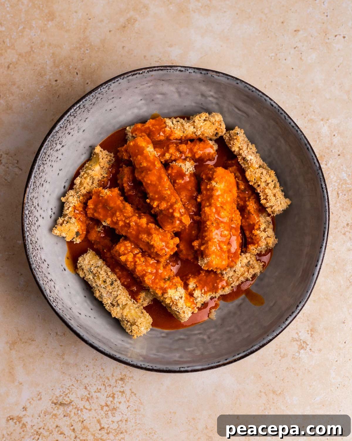 overhead of buffalo sauce poured over tofu wings