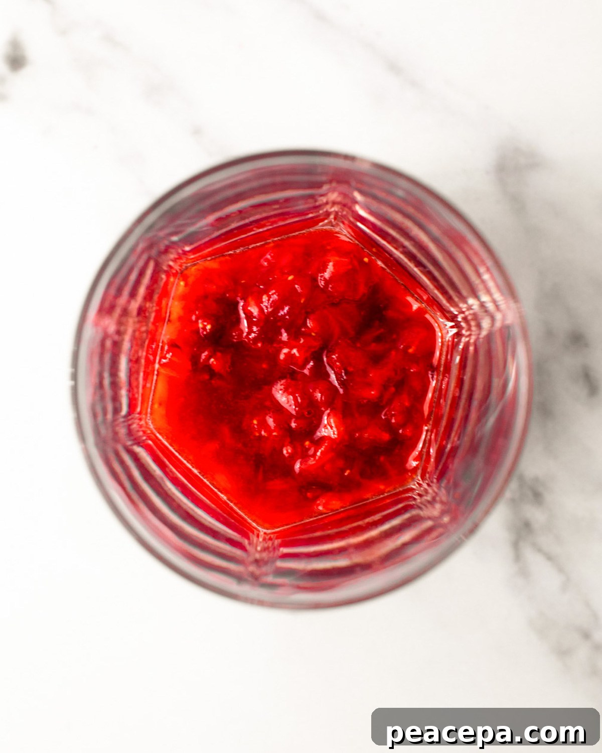 An overhead shot of strawberries muddled in a glass.