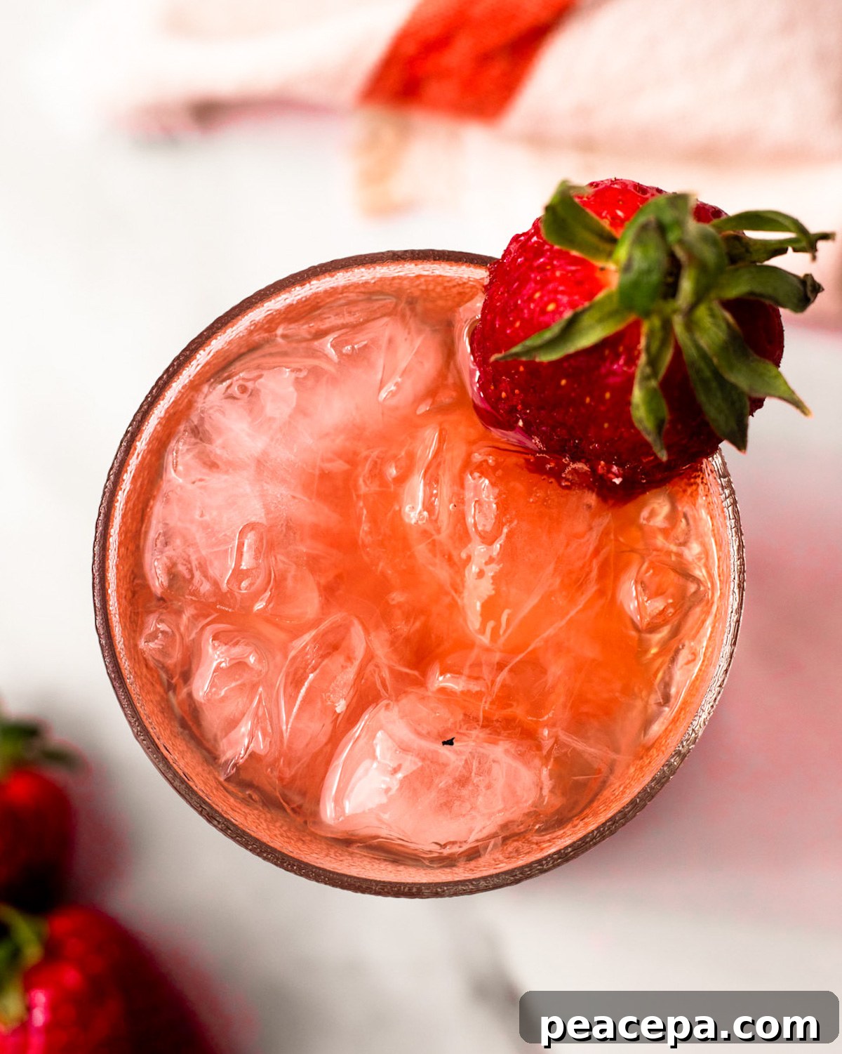 An overhead shot of a glass of strawberry bramble with a strawberry on the side of the glass.