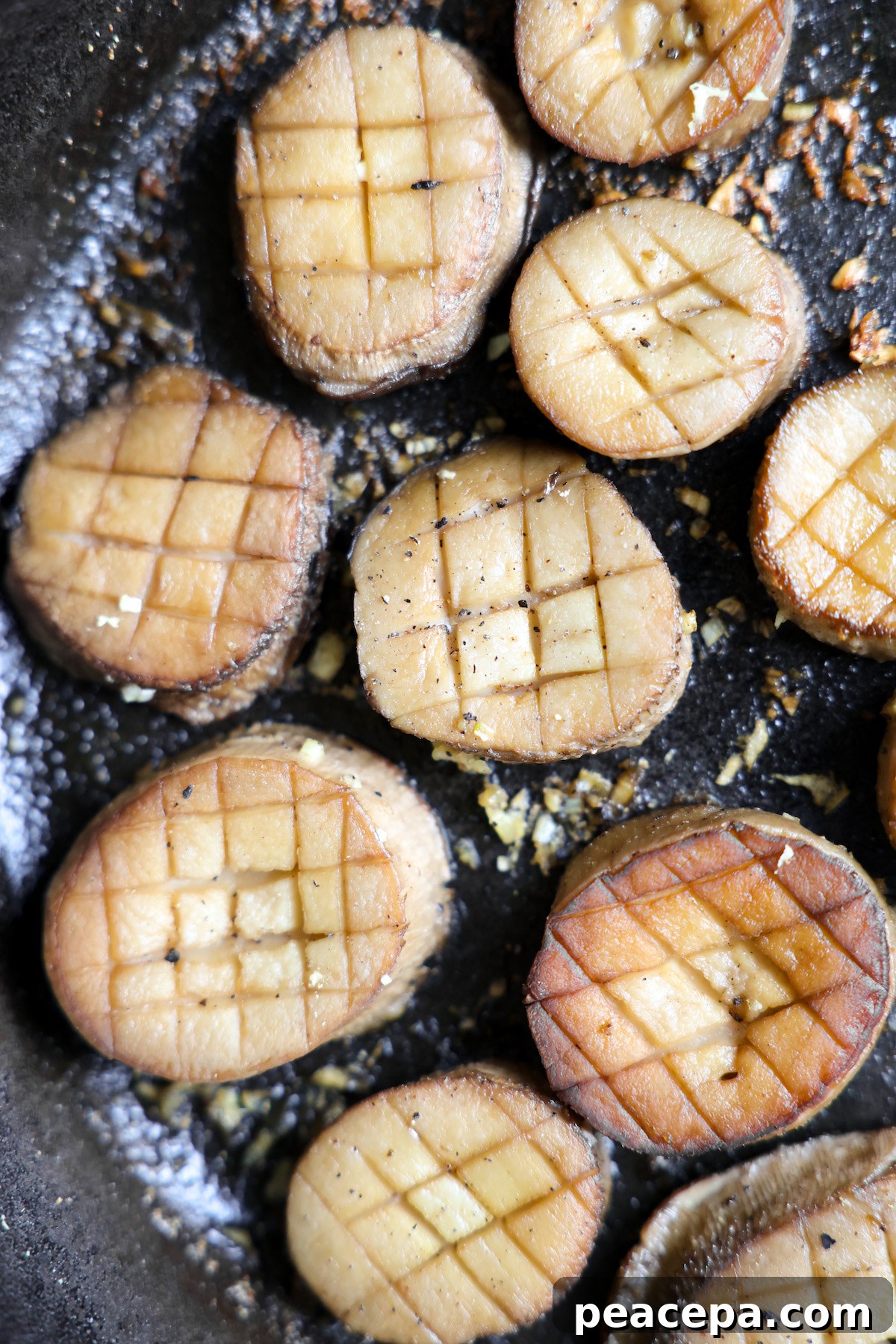 King oyster mushroom slices cooking in a cast iron skillet.