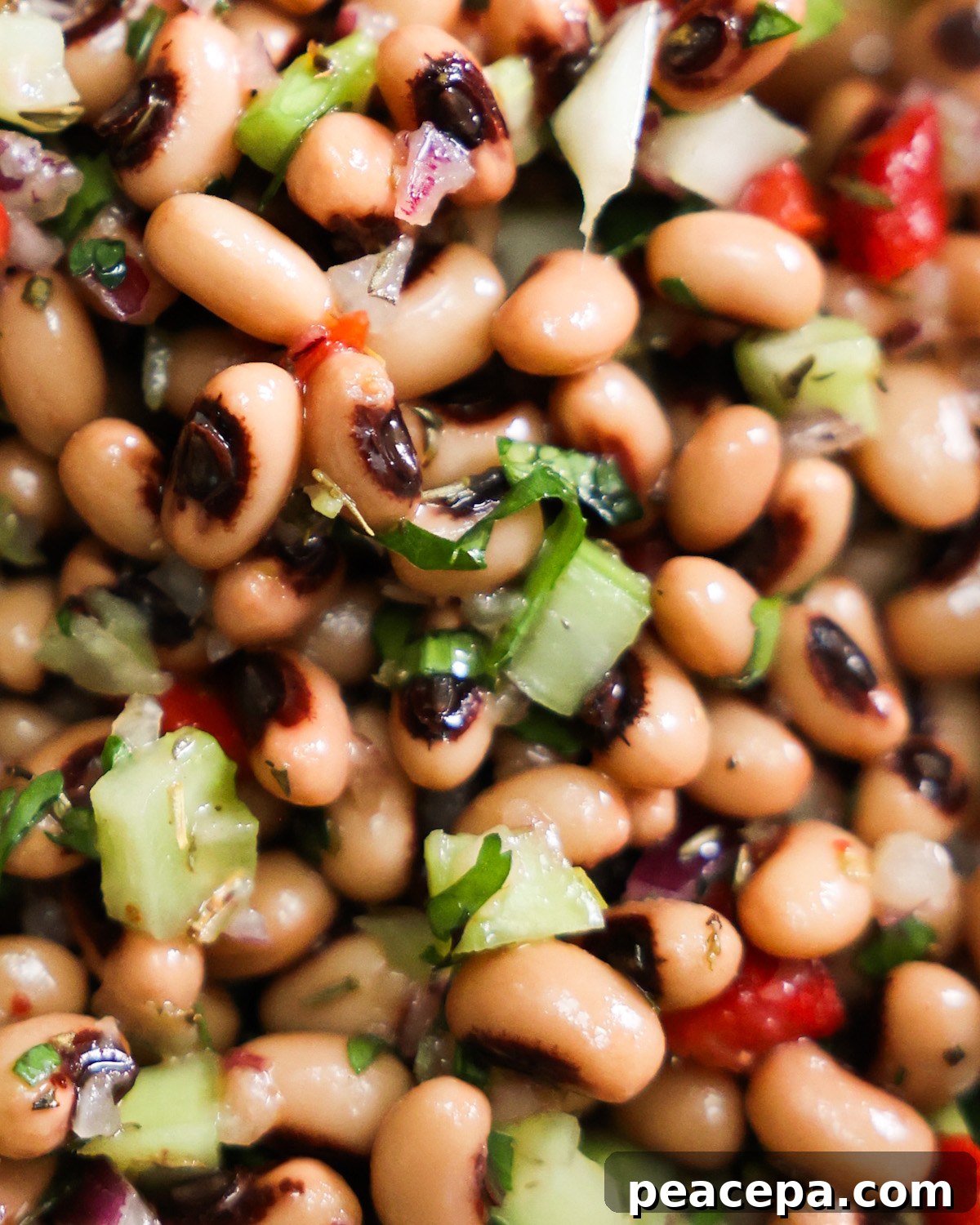 close up image of a black eyed pea salad with bits of celery, red pepper, and parsley seen with the beans. 