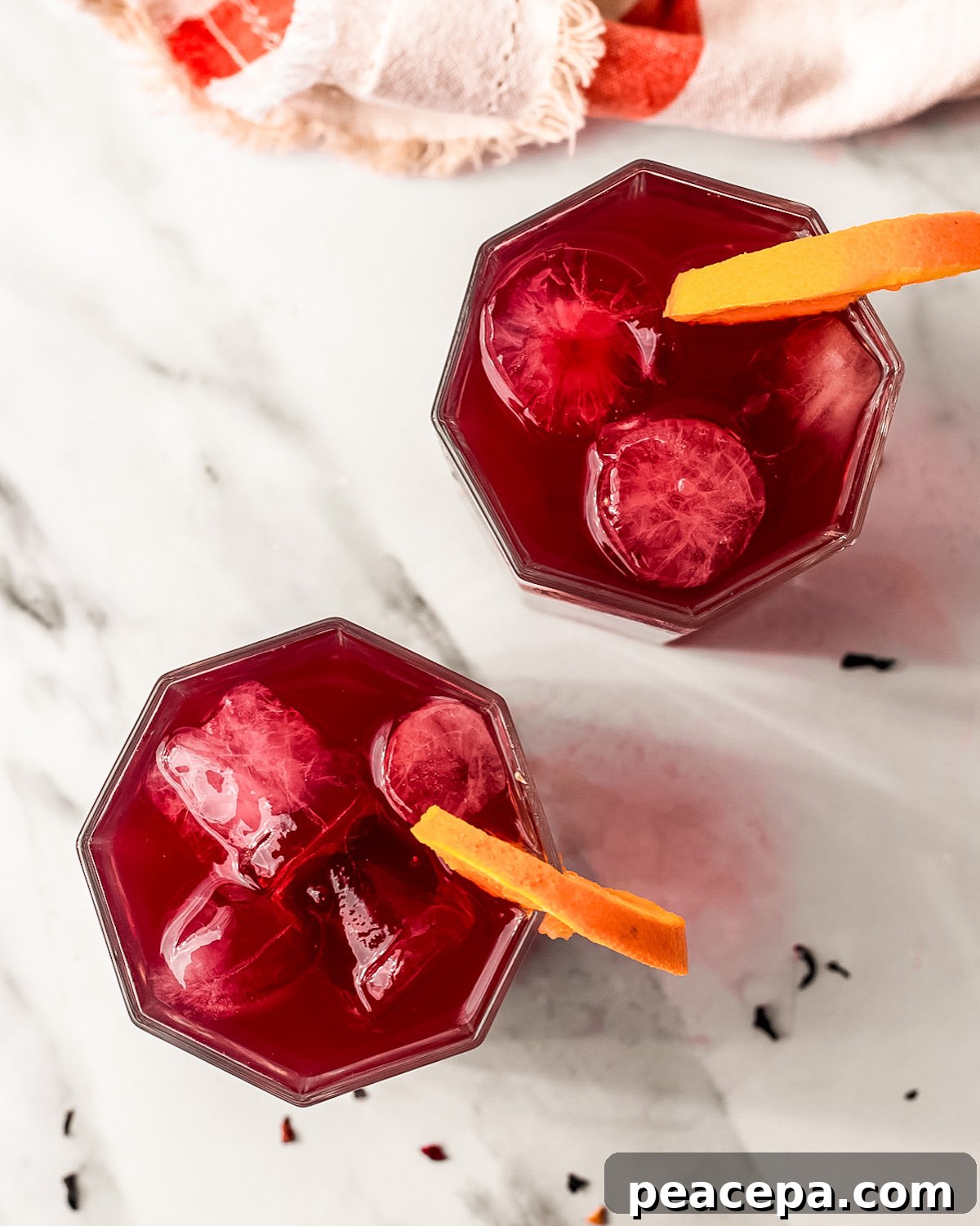 two glasses of bright red tea with orange slices