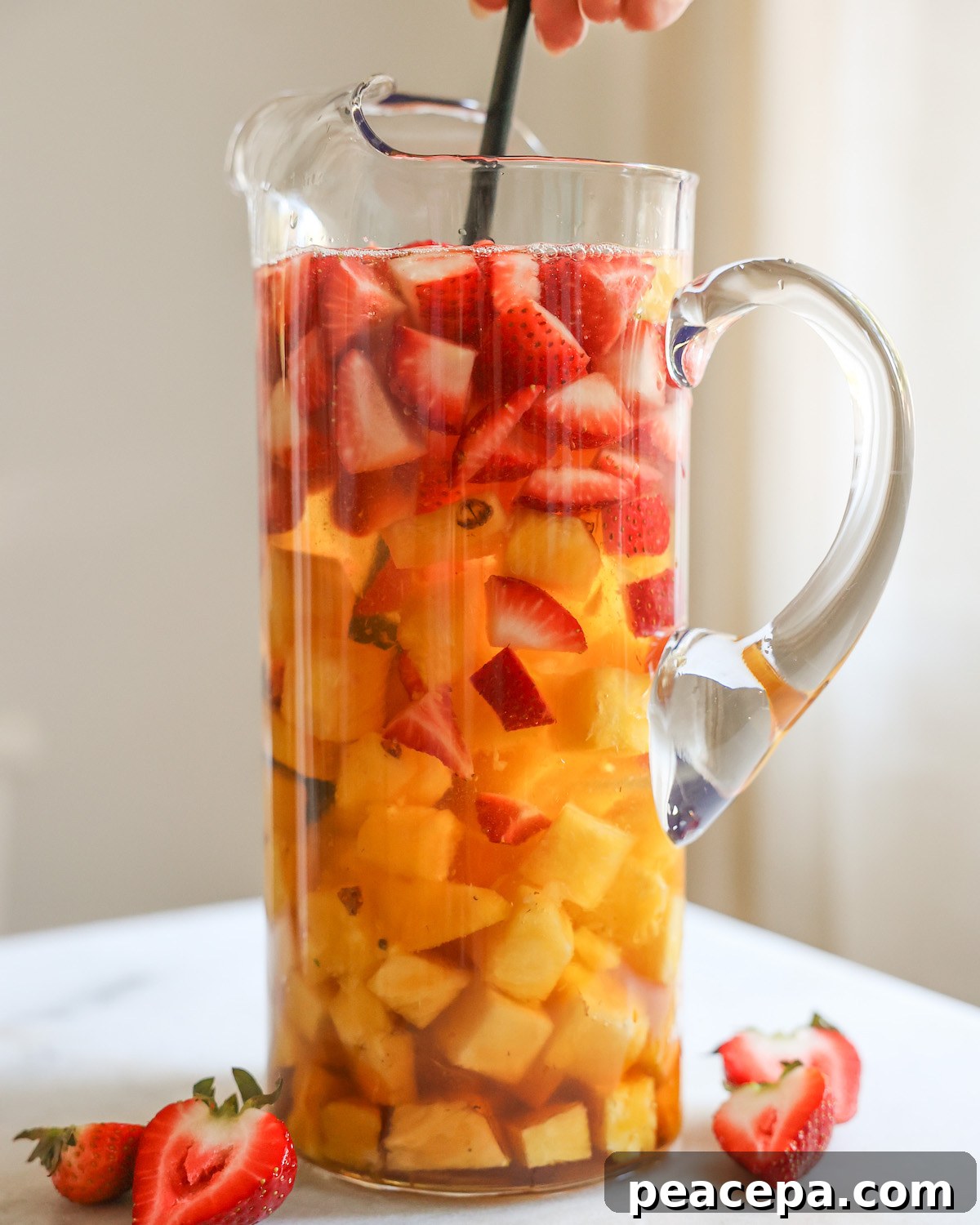 Stirring a pitcher of pineapple summer sangria.