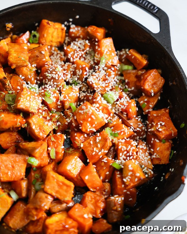 Bright orange glazed sweet potatoes in a black cast iron skillet