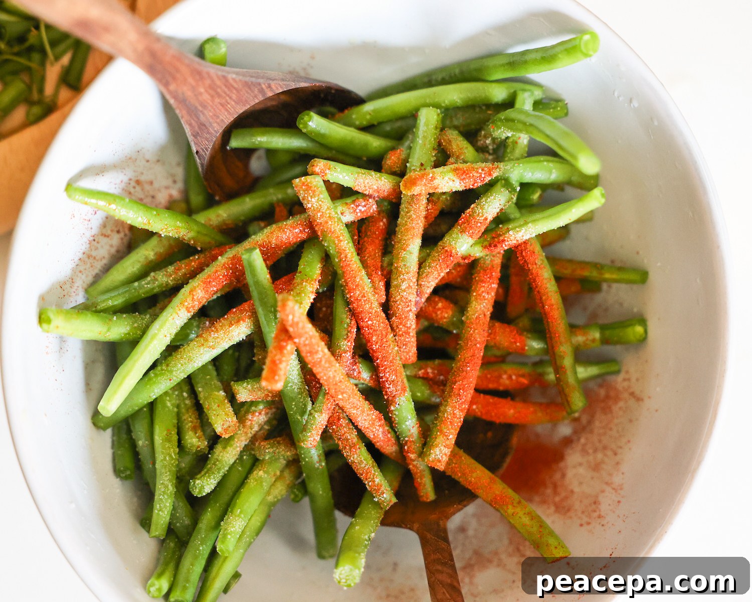 A bowl of trimmed beans covered with spices.