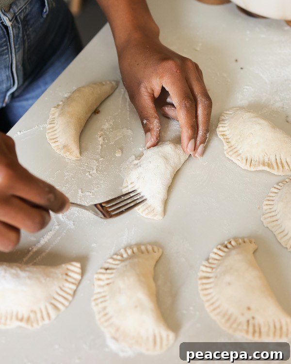 image of jenne sealing the sides of the empanadas with a fork