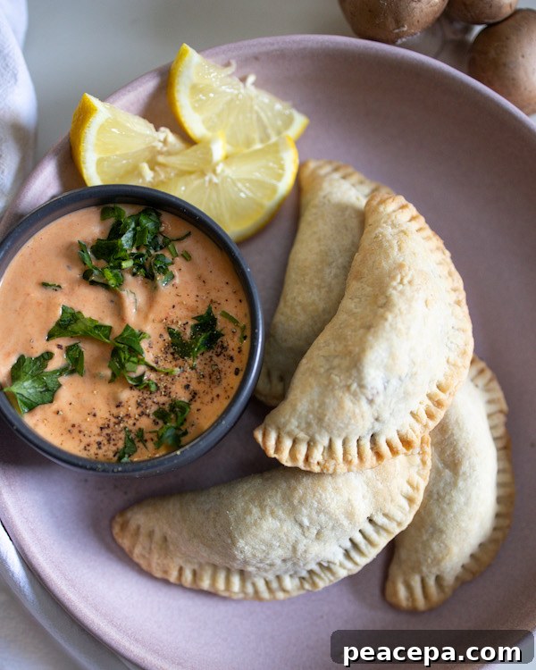 overhead of vegan empanadas on a plate with aoili and lemon slices