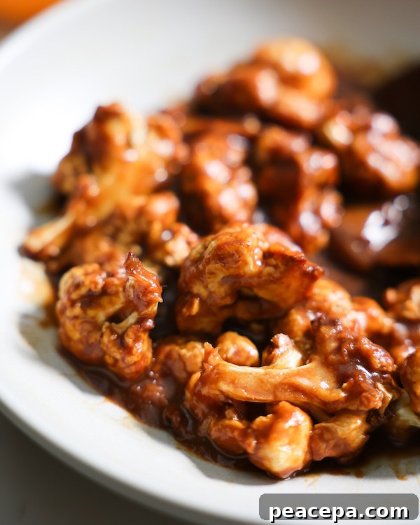 CLOSE UP of saucy orange cauliflower bites in a bowl