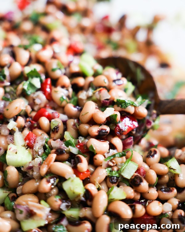 close up of black eyed pea salad in a bowl with spoon