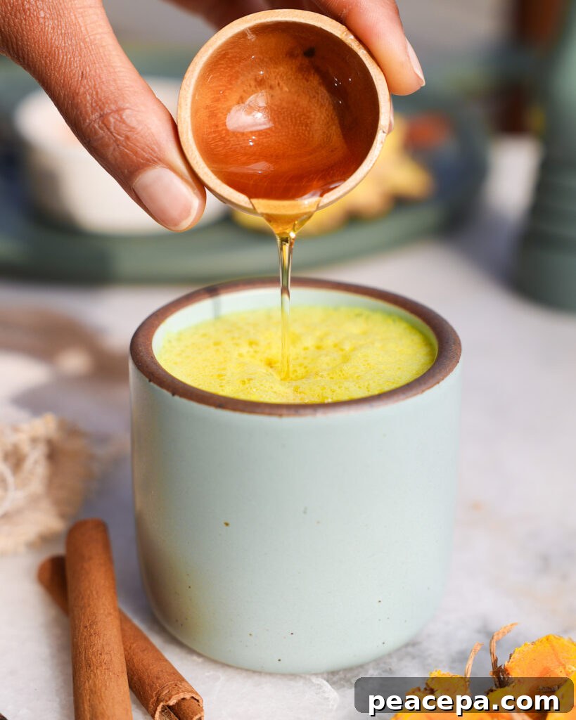 hand pouring agave into turmeric latte