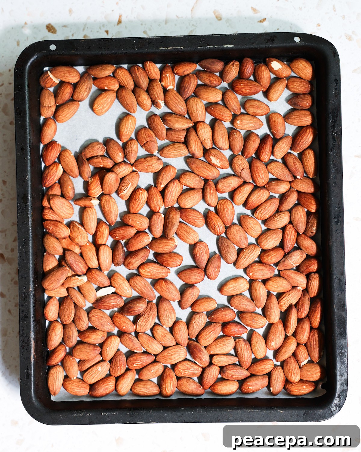 An overhead shot of a pan of tamari almonds before roasting.