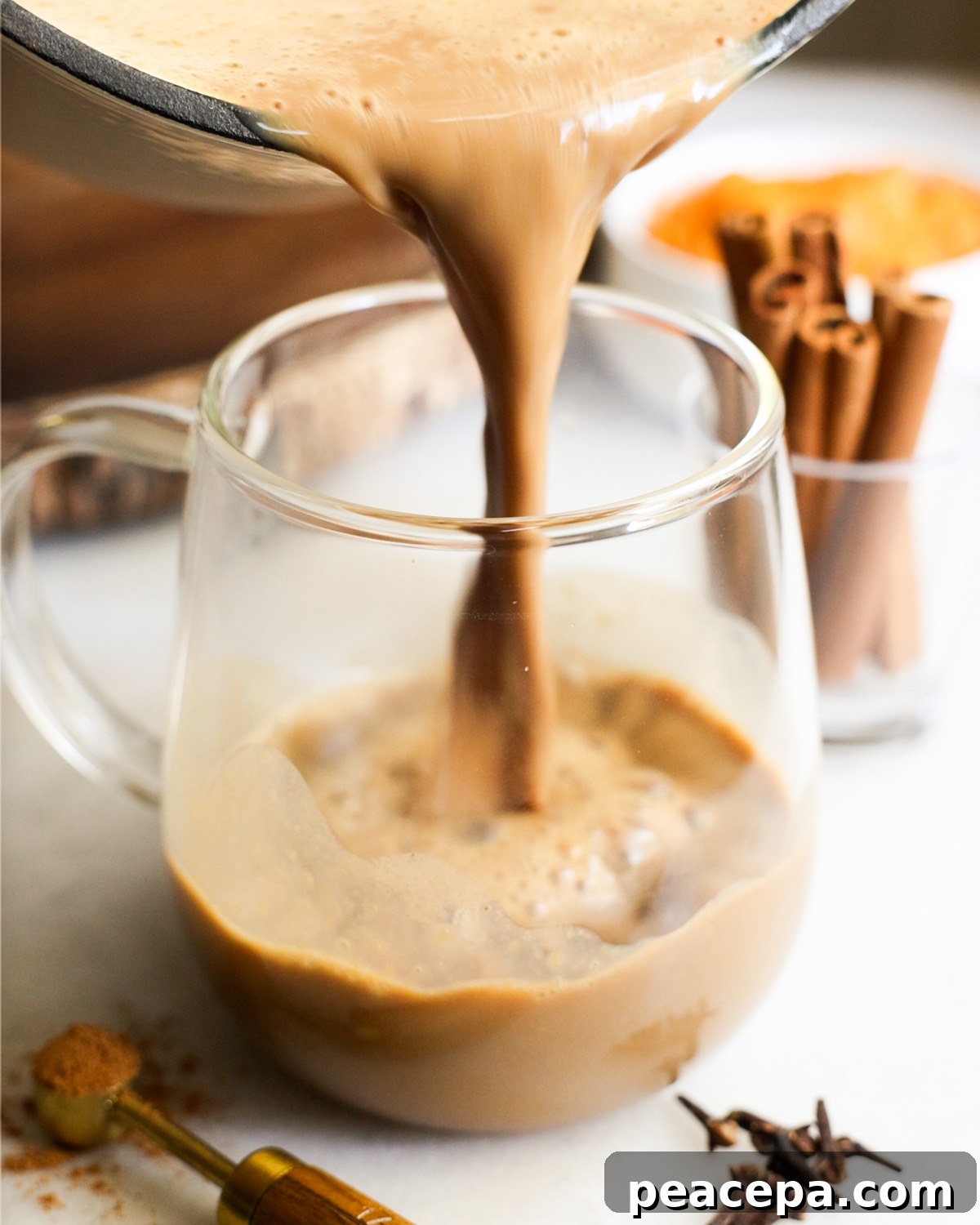 side view of pouring sweet potato latte into a clear mug