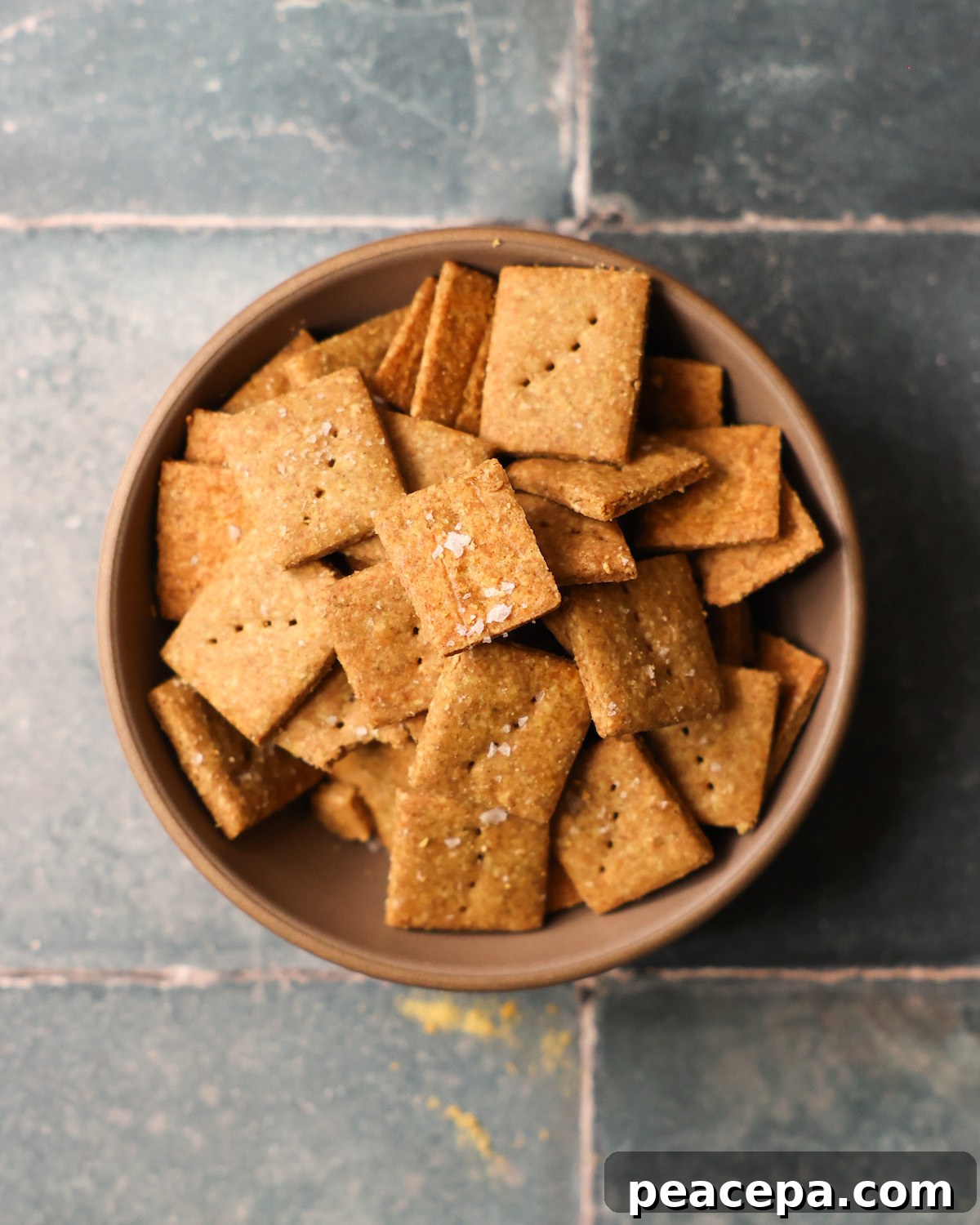 An overhead shot of a bowl of pumpkin seed crackers in a bowl on the counter.
