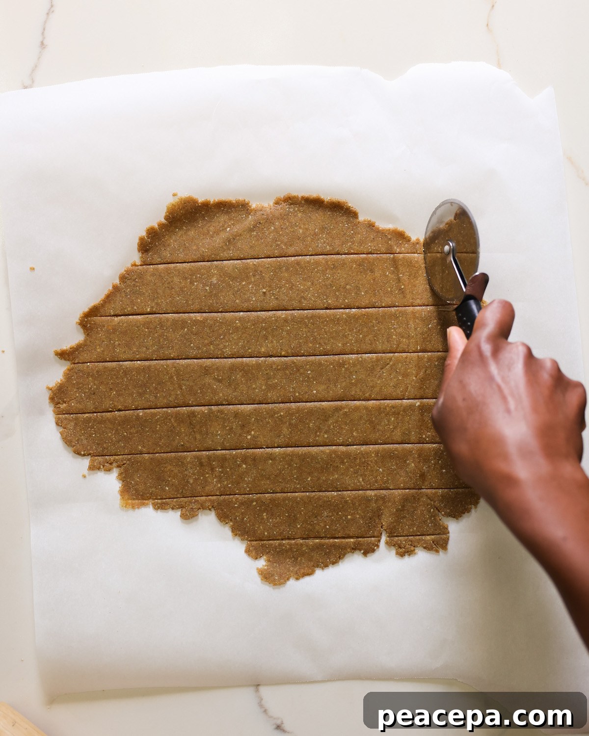 Cutting the sheet of pumpkin cracker dough into small pieces.
