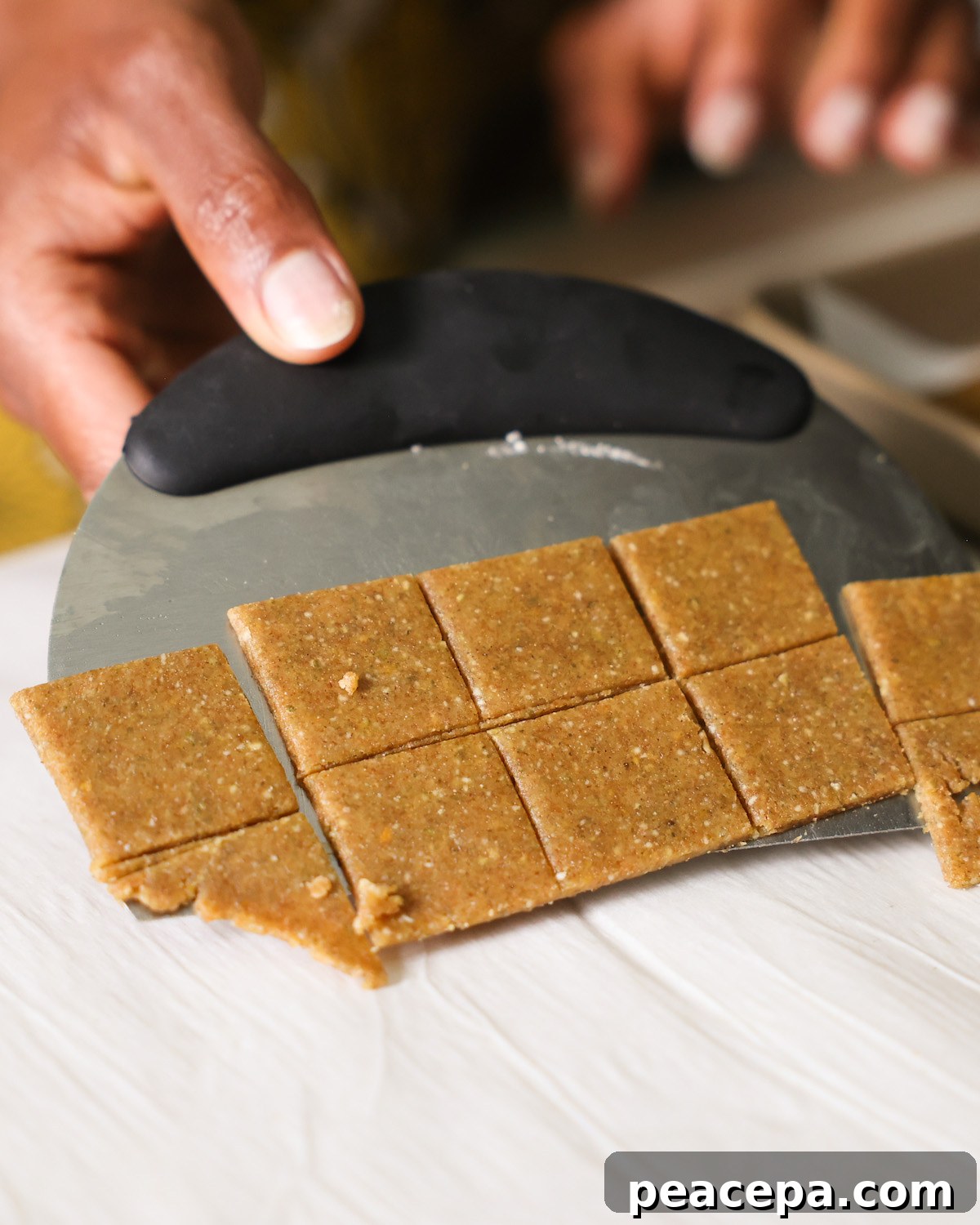 Scraping the "cheesy" pumpkin seed crackers off of the counter with a bench scraper.
