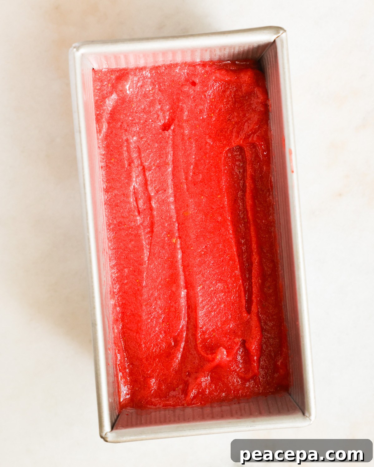 An overhead shot of a pan of strawberry sorbet before freezing.