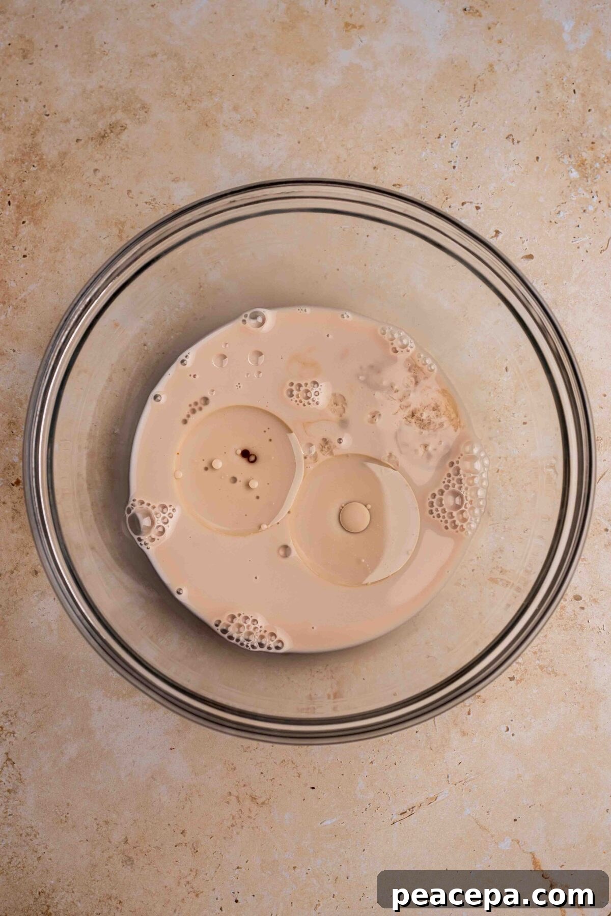 An overhead shot of the wet mixing ingredients in a glass mixing bowl.