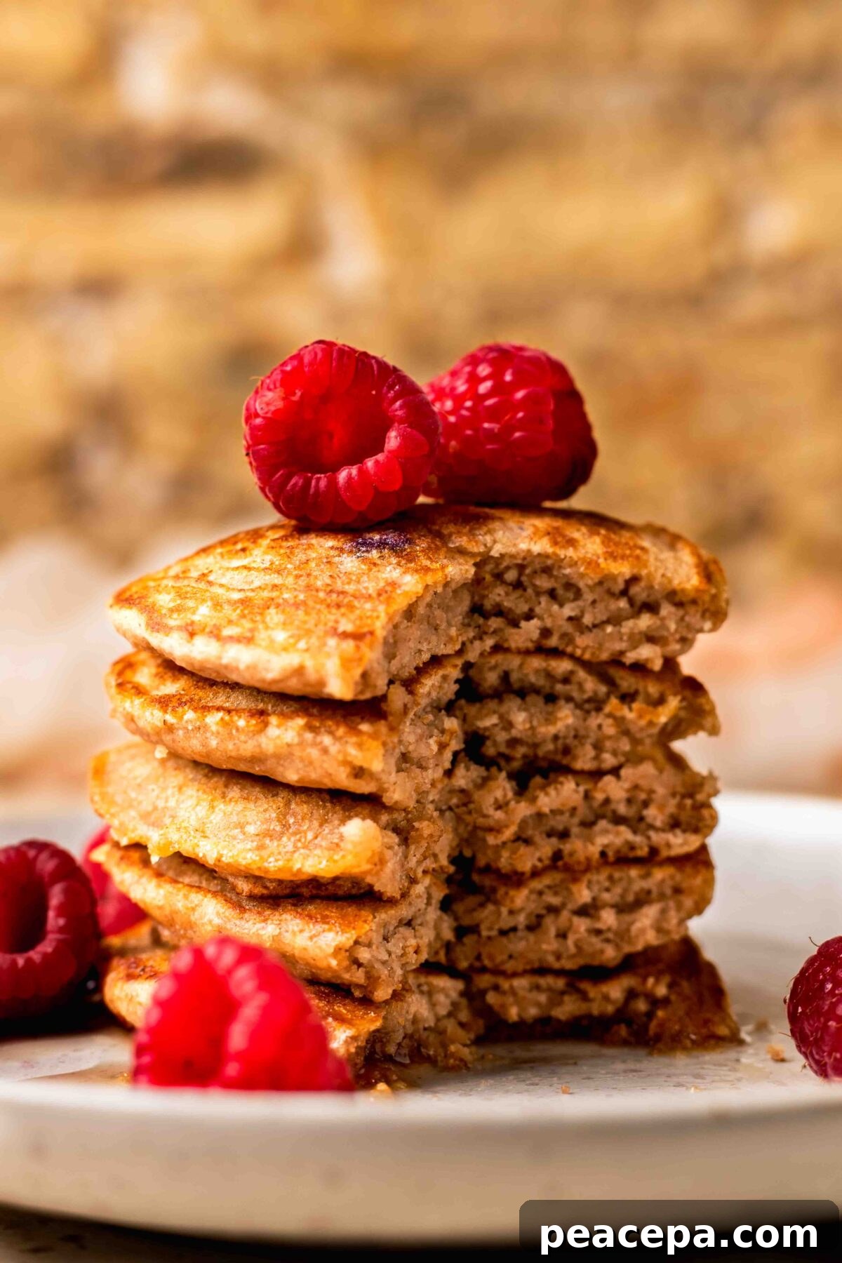 An up-close side shot of a small stack of spelt pancakes with a forkful taken out of it.