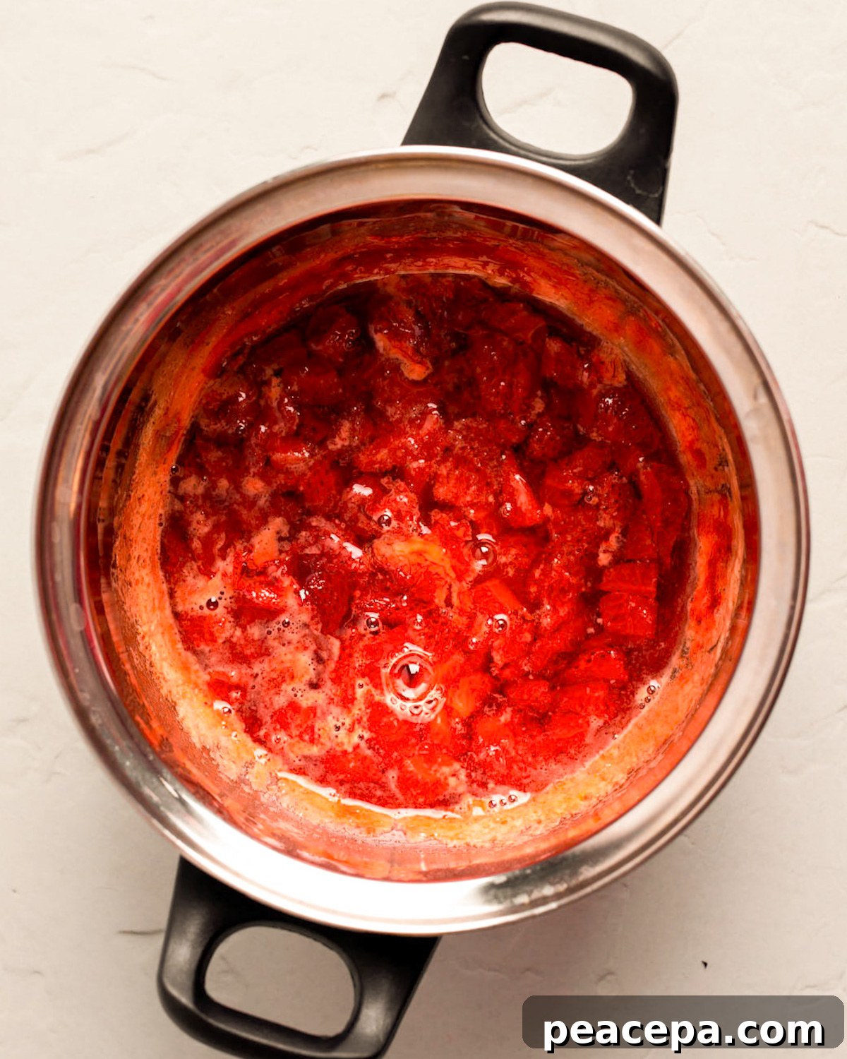 An overhead shot of the simmered strawberries in a small pot on the counter.