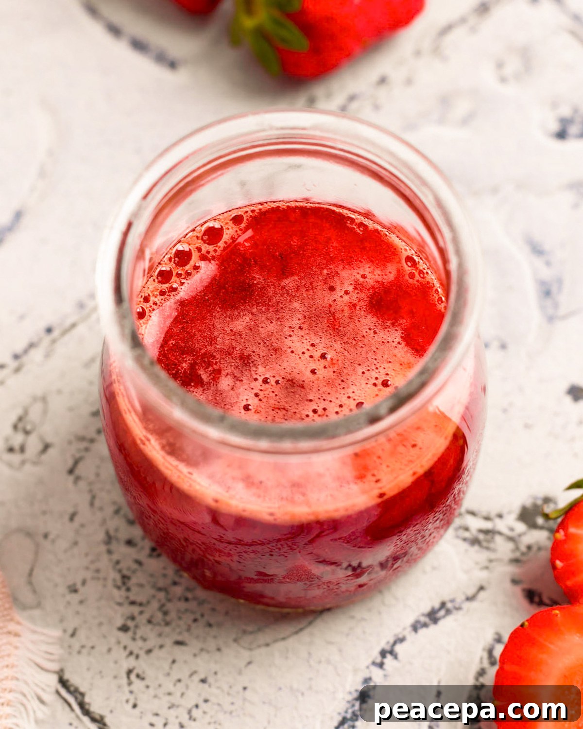 An up-close angled shot of a small cup of the simmered strawberry mixture.