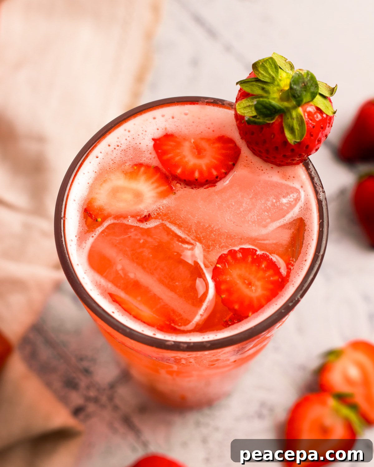 A close-up angled overhead shot of a tall glass of strawberry soda.