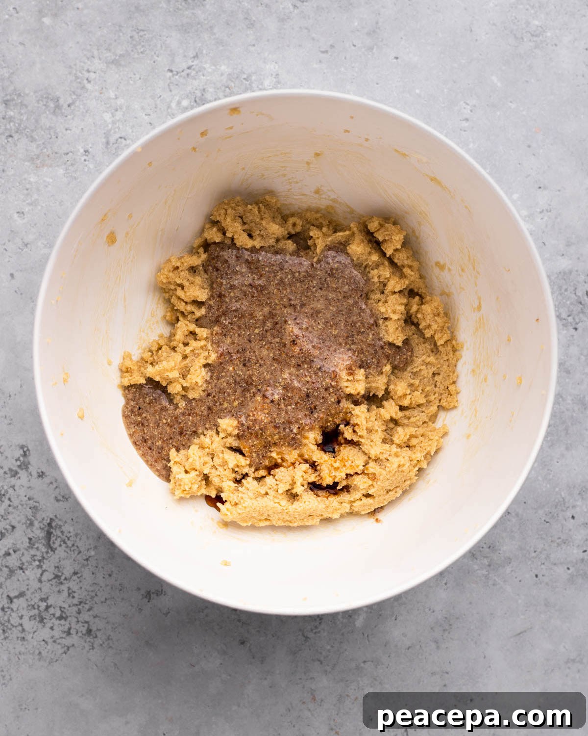 overhead of flaxseed egg added to bowl of creamed vegan butter and sugar