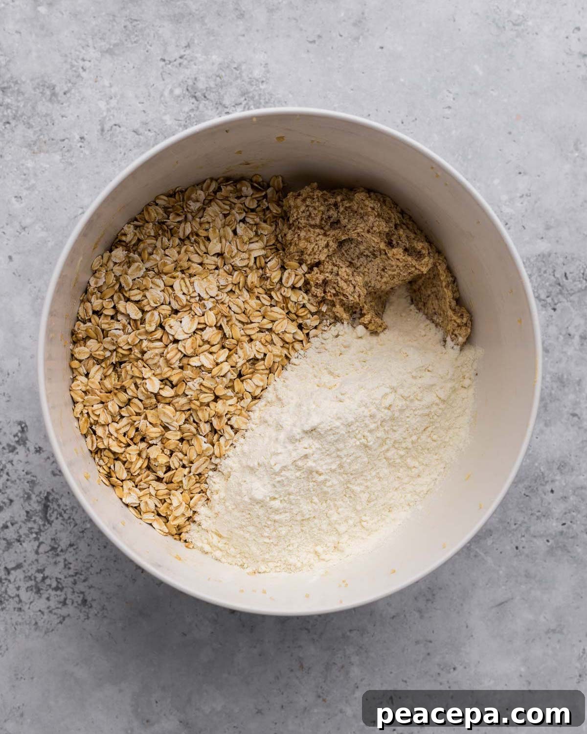 overhead of flour and oats added to bowl