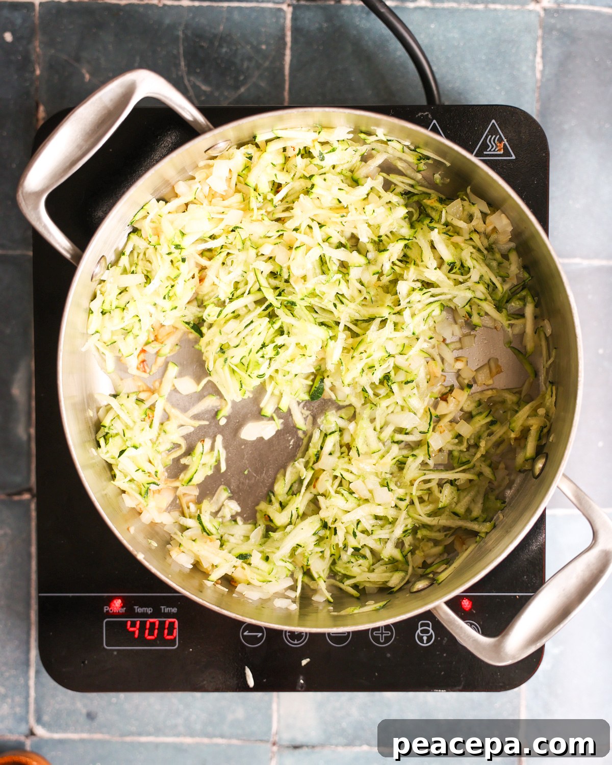 overhead of shredded zucchini added to pan