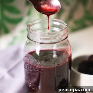 spoon drizzling blackberry syrup over jar