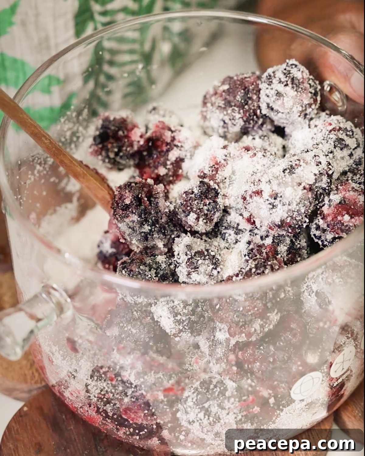 overhead of sugar being stirred into blackberries