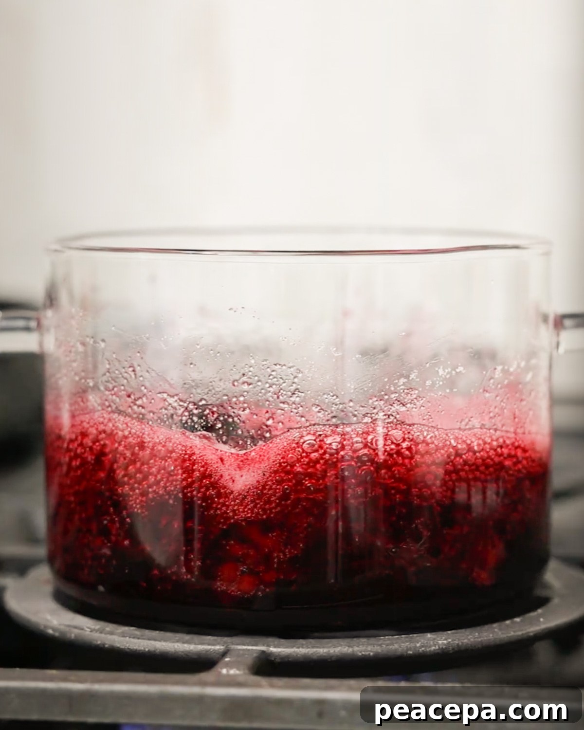 blackberry syrup simmering in glass pot