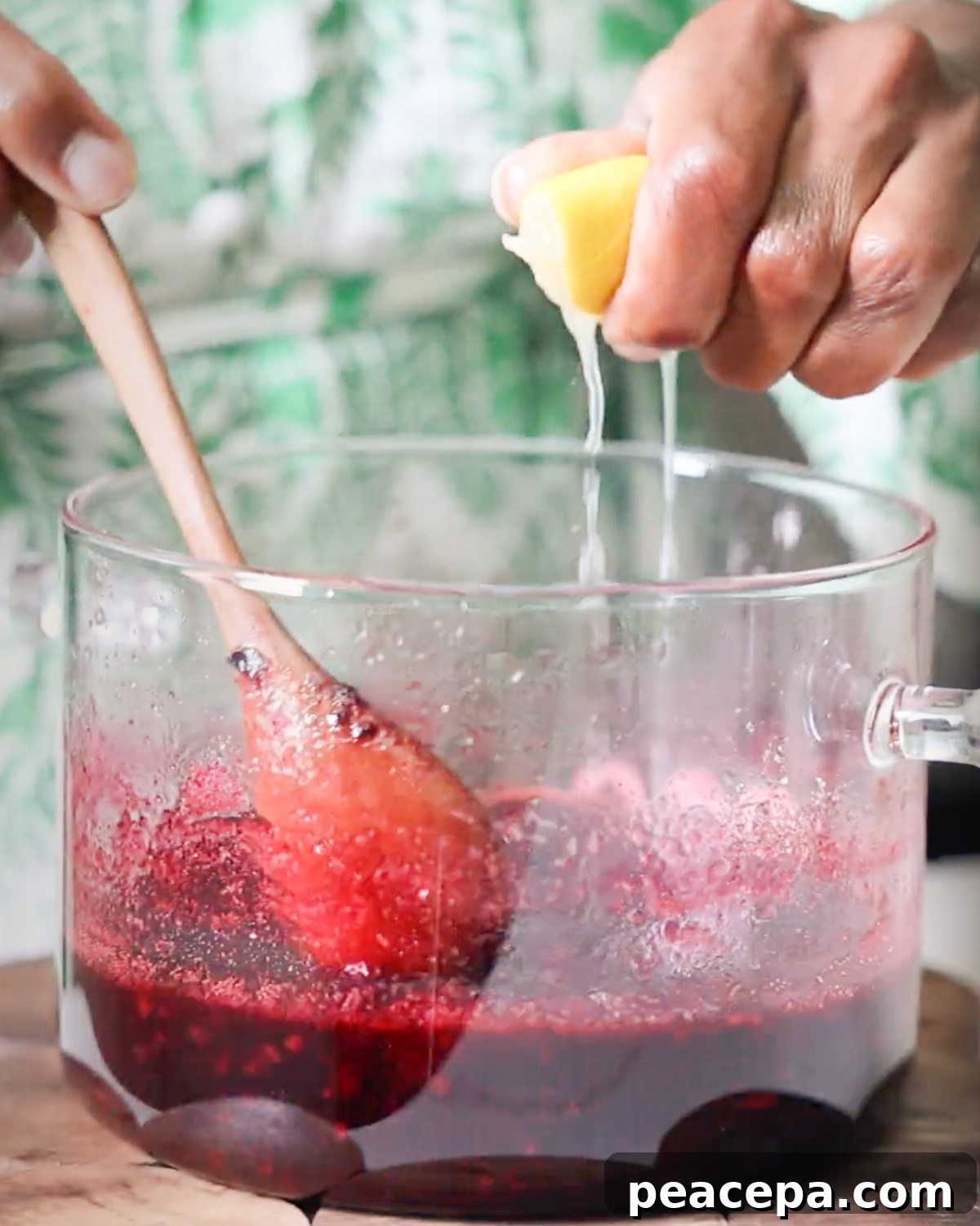 squeezing lemon juice into blackberry syrup