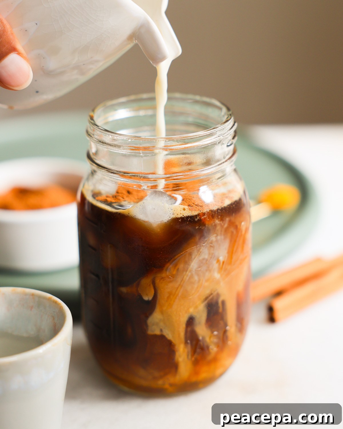 pouring oat milk into glass jar with espresso and other ingredients