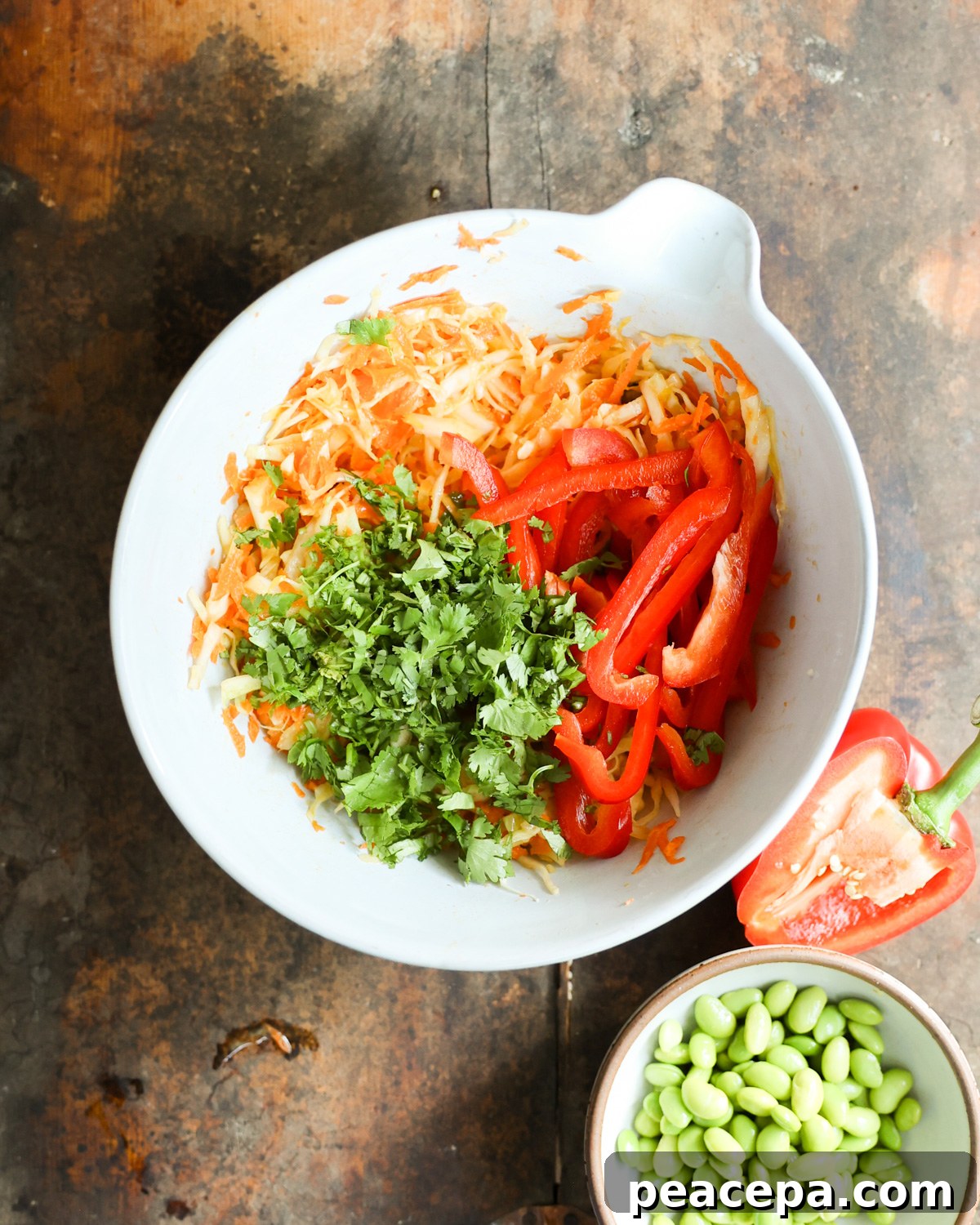 A mixing bowl of carrots, cabbage, peppers, and cilantro.