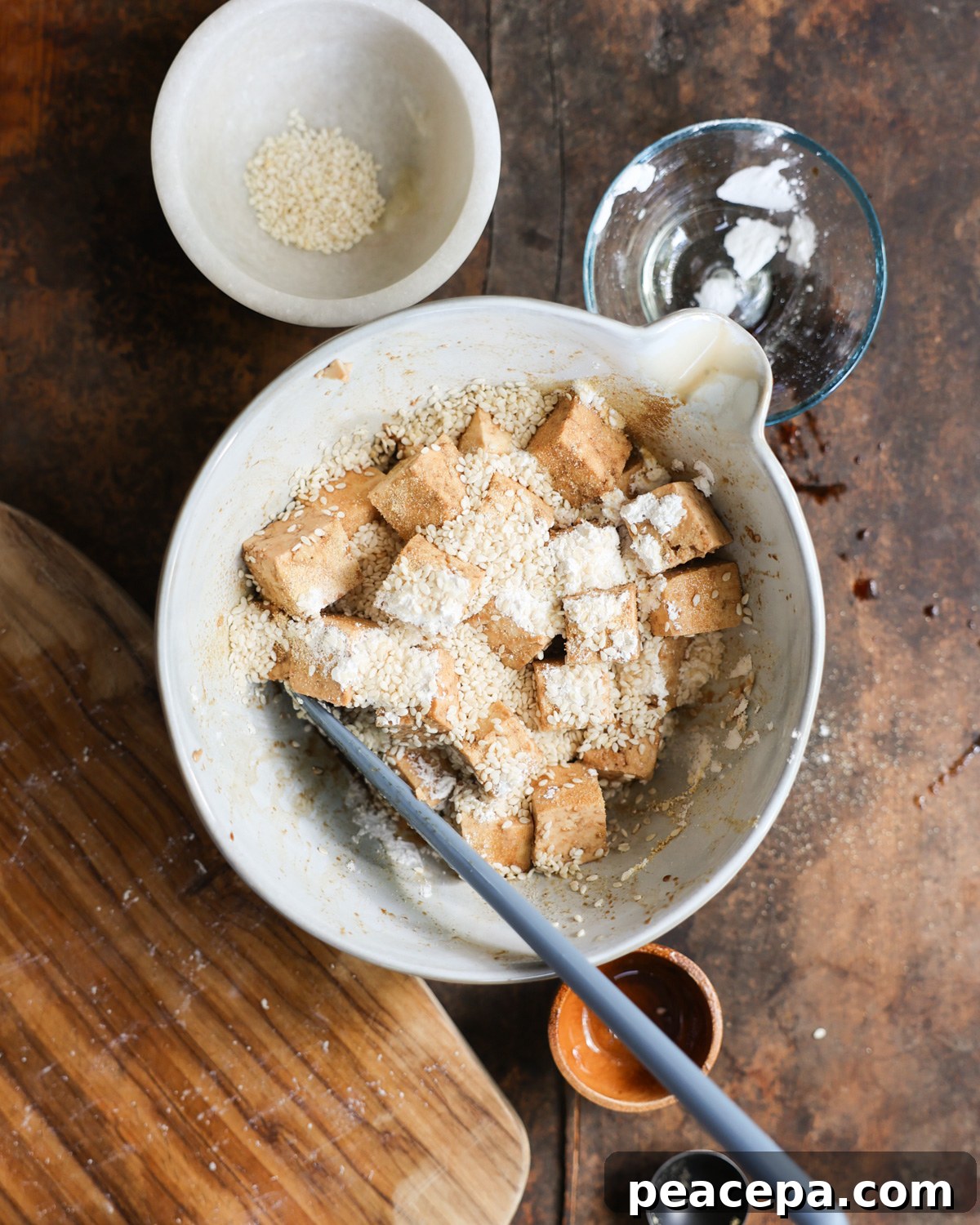 Tofu cubes with seasonings in a white bowl.