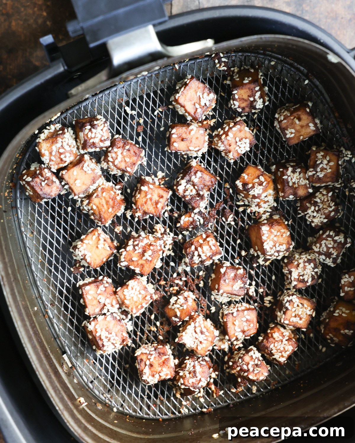 Cooking the air fryer tofu cubes in the air fryer basket.