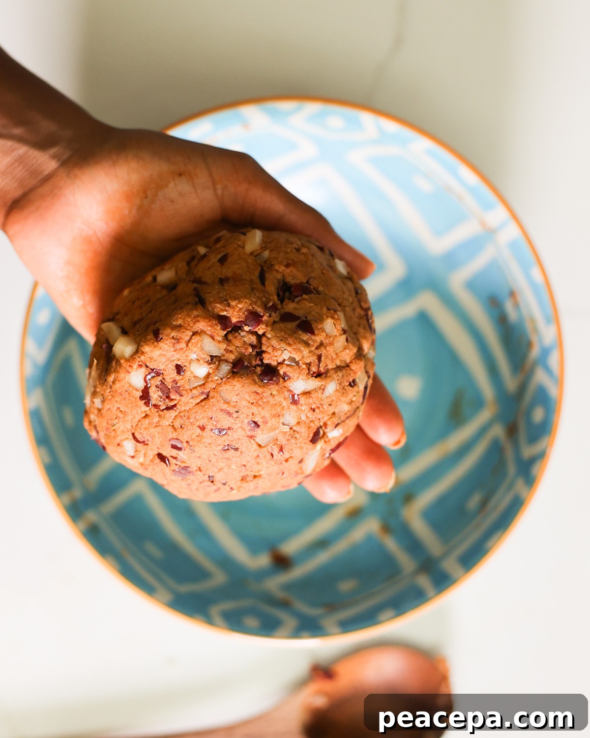 A hand holding a ball of vegan sausage dough before shaping.