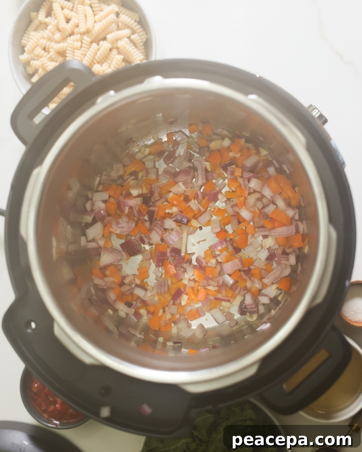 An overhead shot of onions and carrots sauteing in an Instant Pot.