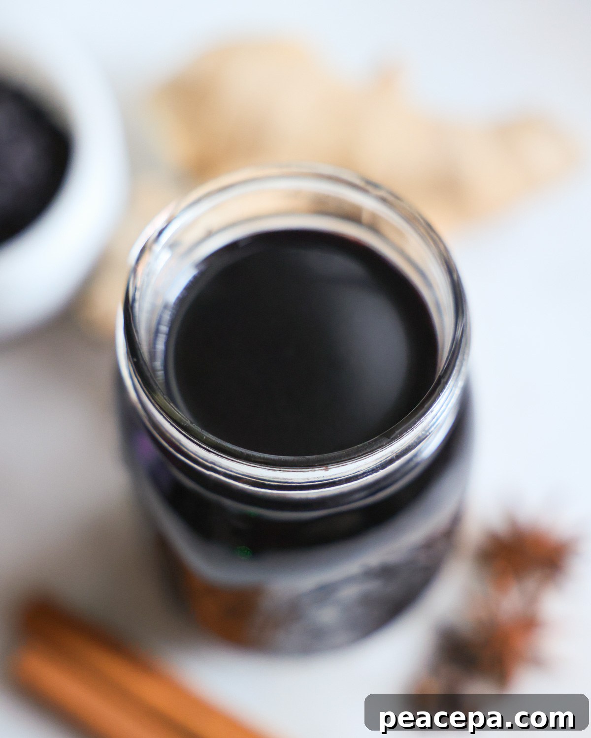 An up-close overhead shot of a small jar of elderberry syrup.
