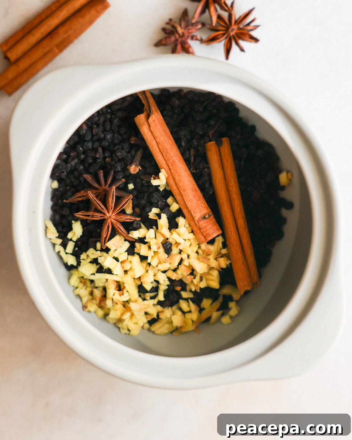 An overhead shot of a crock of dried elderberries with spices.