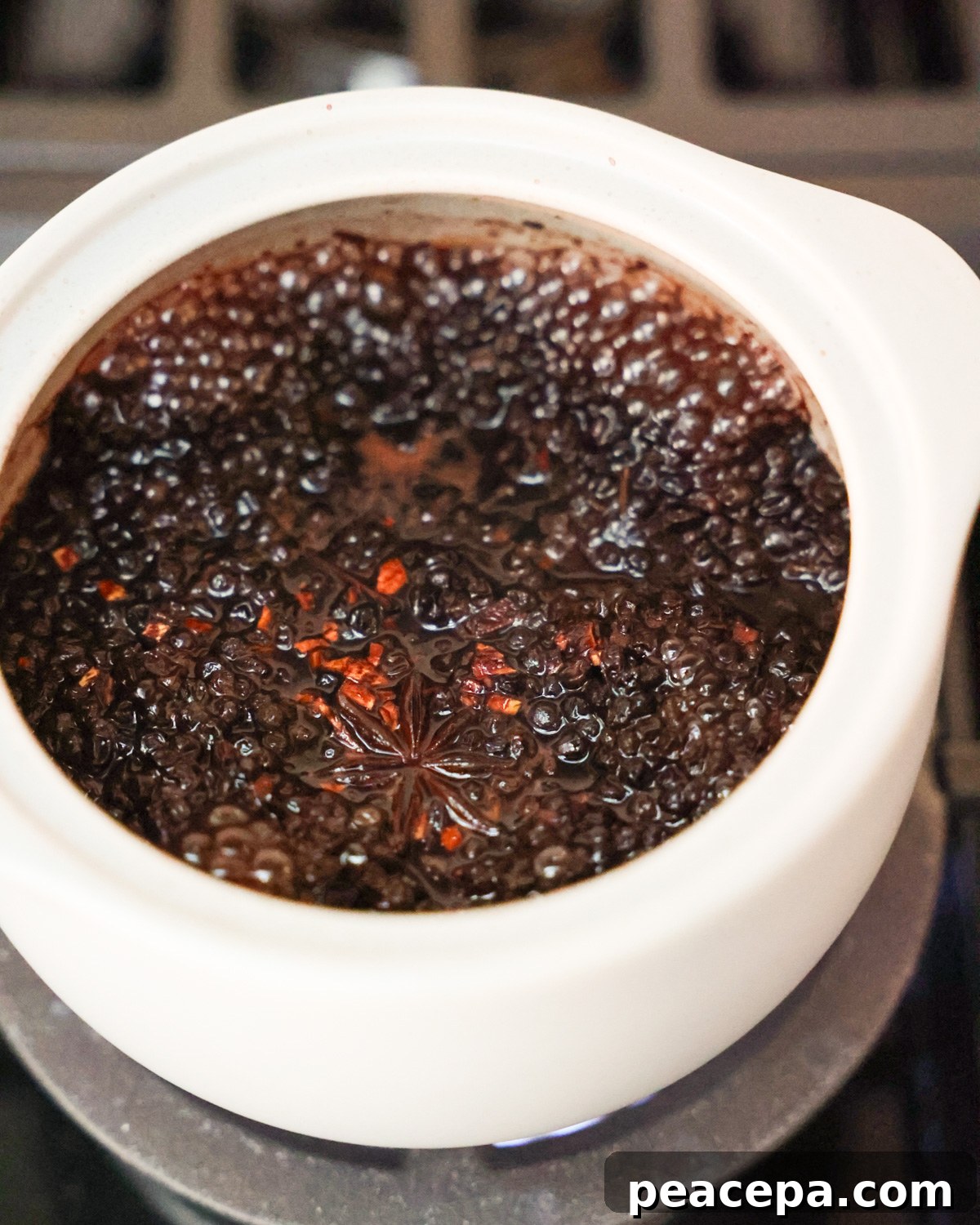 An up-close side shot of the elderberries simmering in water with spices.