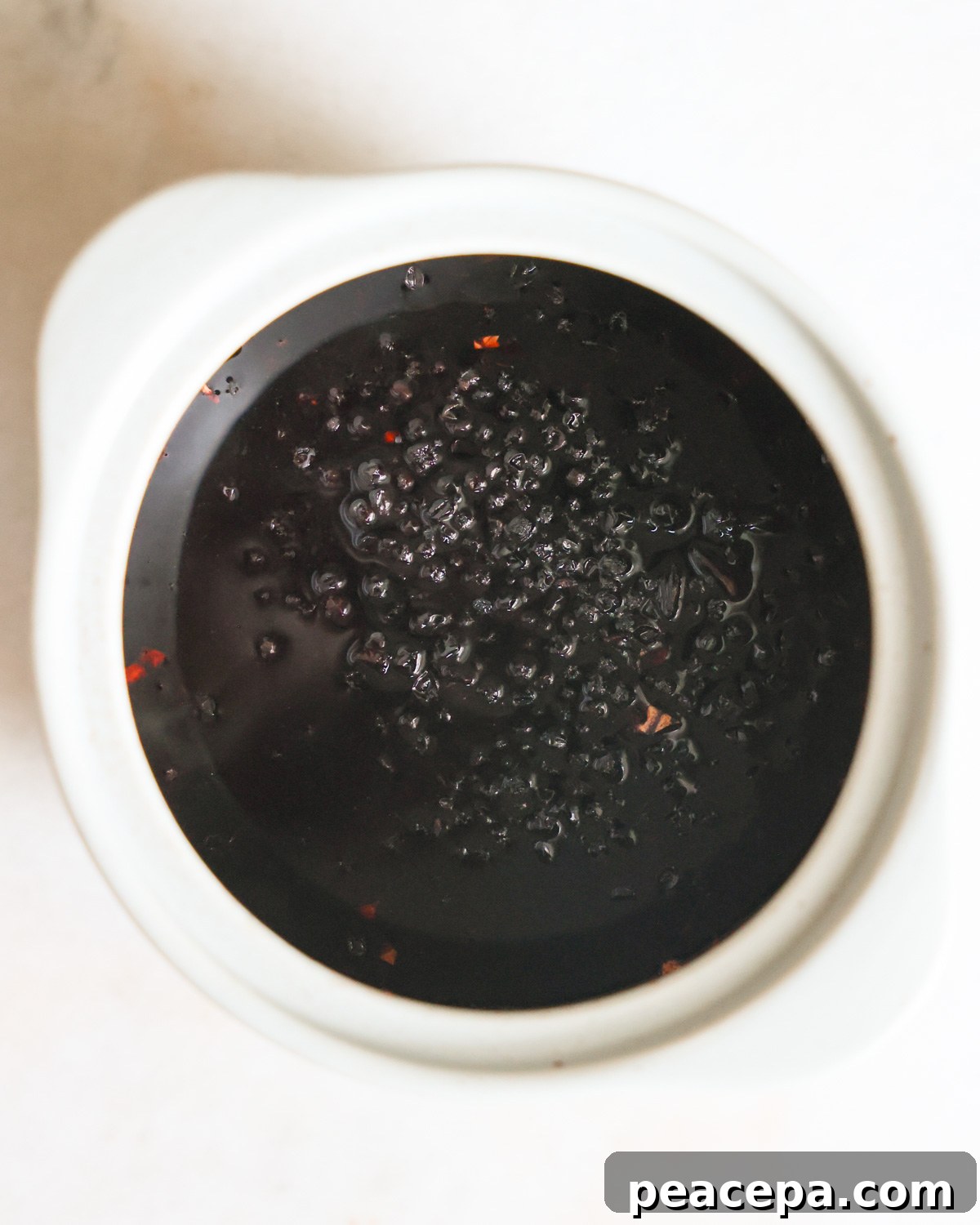 An overhead shot of the elderberries simmered in water with spices.